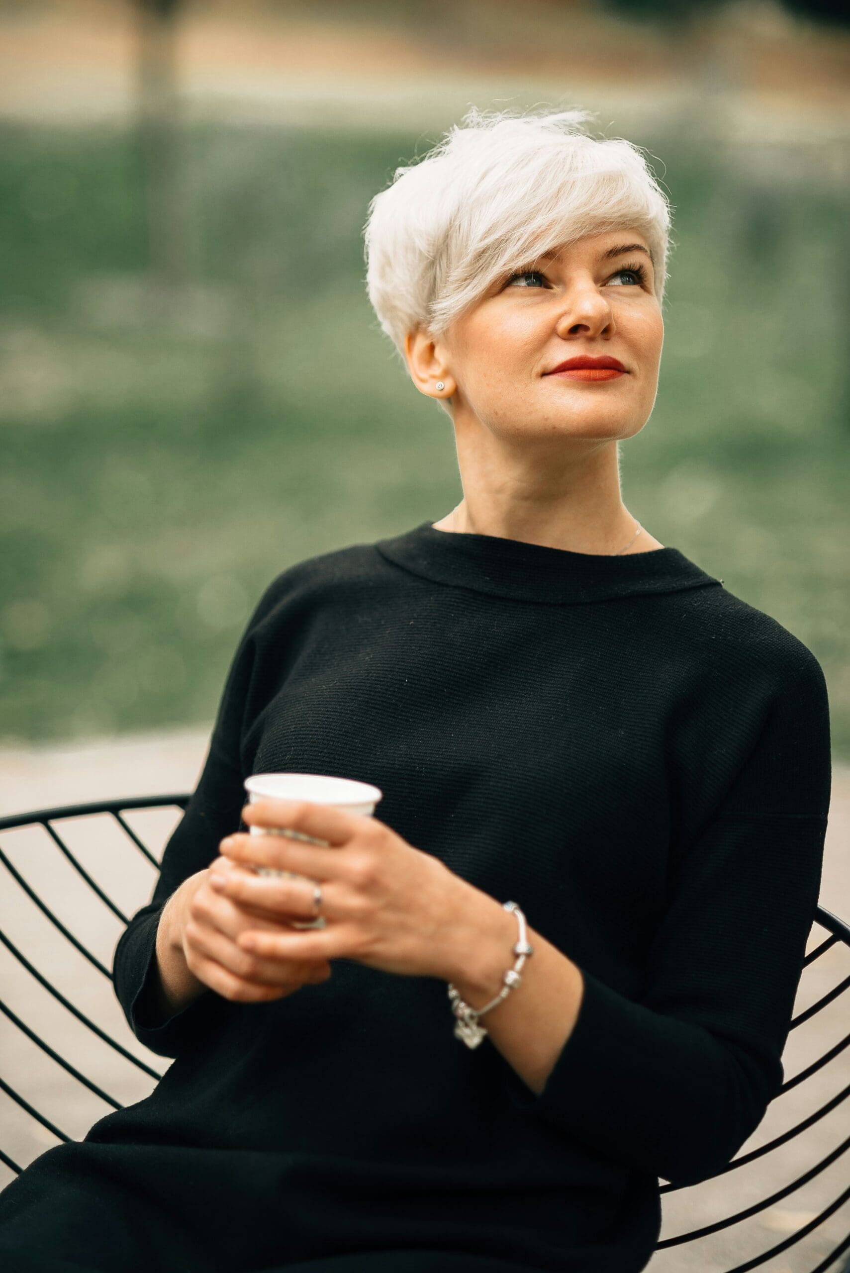 woman with short hair and red lipstick holding a coffee cup
